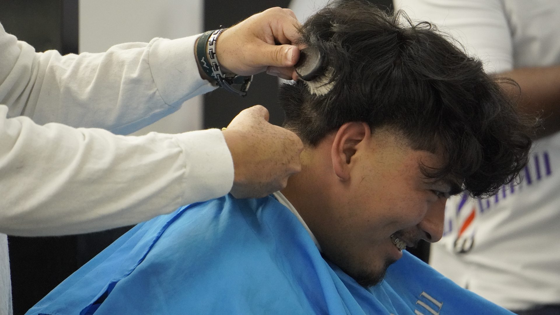 Student barber smiling during a haircut